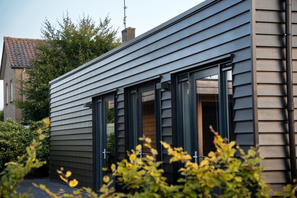 Modern zwart houten woning met grote ramen en strakke afwerking.