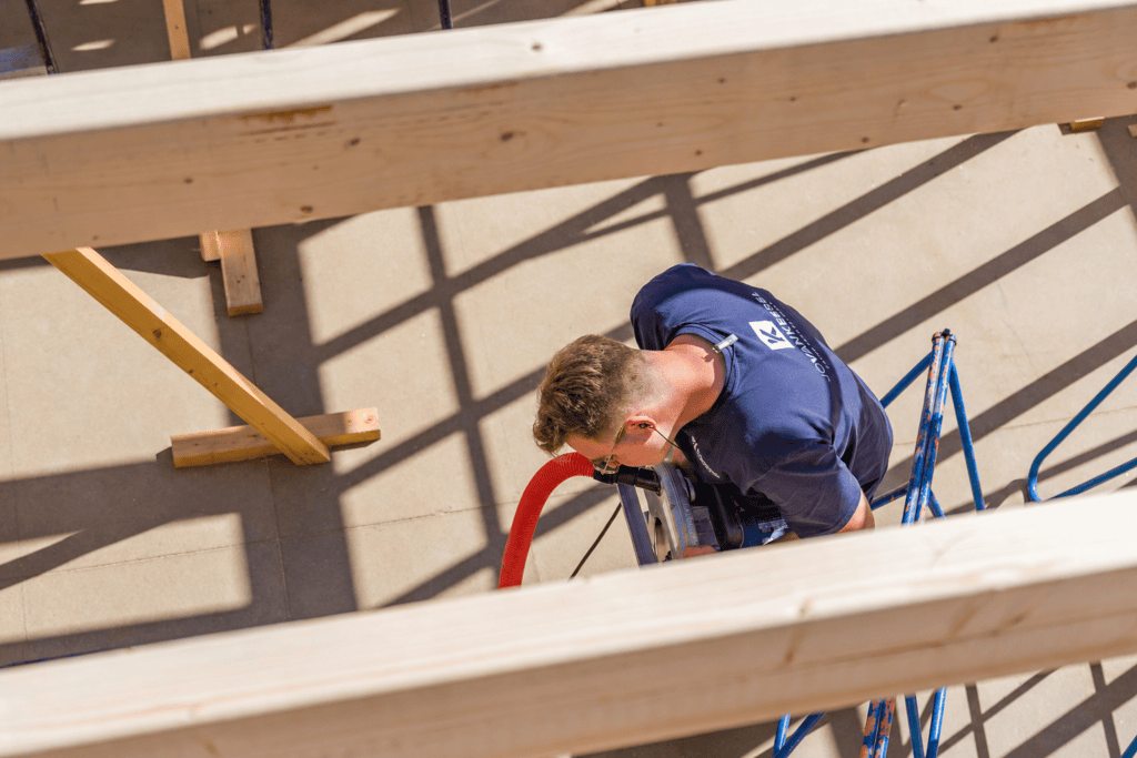 Bouwvakker werkt aan houten constructie op bouwplaats, focus op vakmanschap en bouwproces.