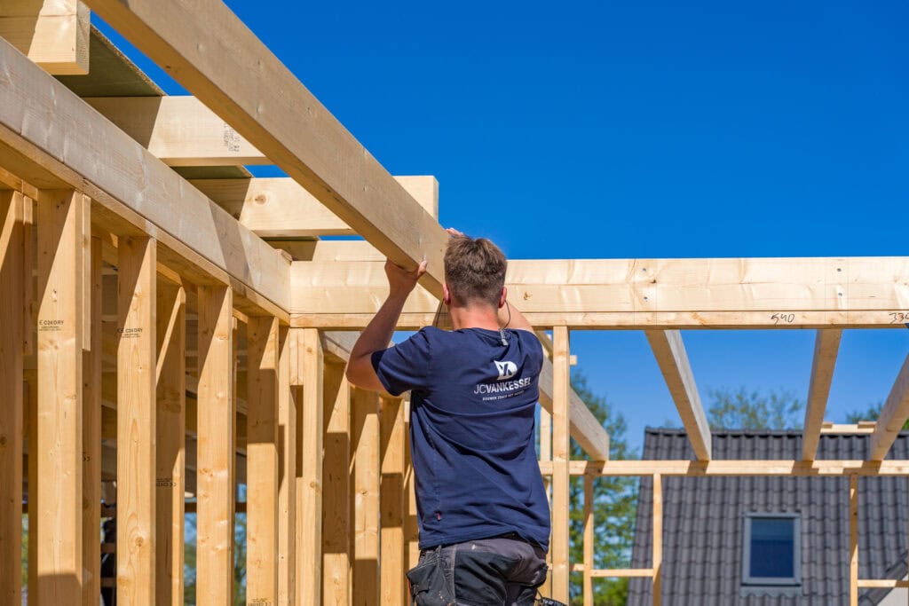 Vakman bouwt houten frame voor woning of aanbouw.