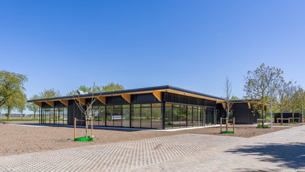 Modern schoolgebouw met grote glazen ramen en houten afwerking, gebouwd door JCVANKESSEL BOUW.