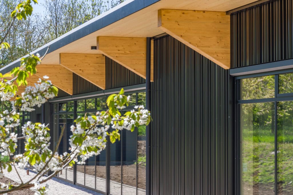Moderne woning met houten en stalen gevels, grote ramen en overkapping, gebouwd door JCVANKESSEL BOU.