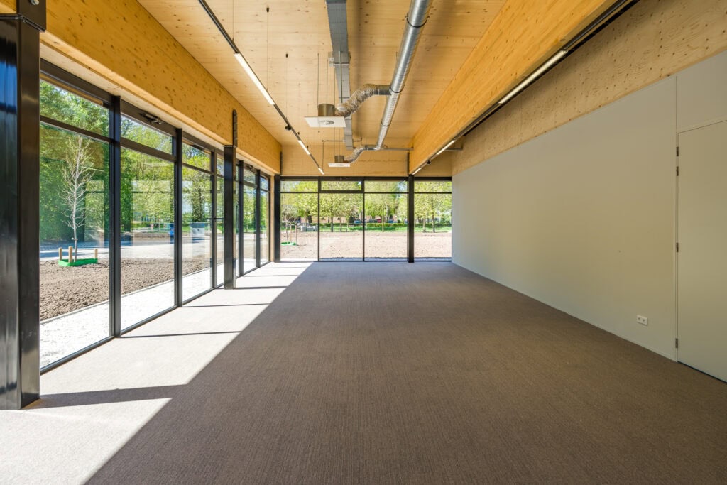 Ruime kantoorruimte met grote ramen, houten plafond en moderne afwerking.