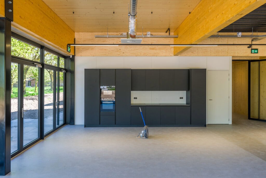 Moderne keuken met strakke zwarte kasten en grote ramen voor natuurlijk licht.