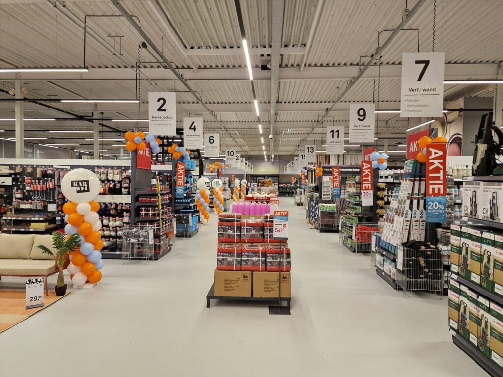Binnenkant van een bouwmarkt met gangpaden en aanbiedingen.