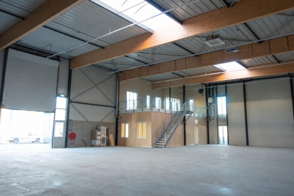 Binnenkant van een grote industriële hal met houten plafond en metalen structuur.