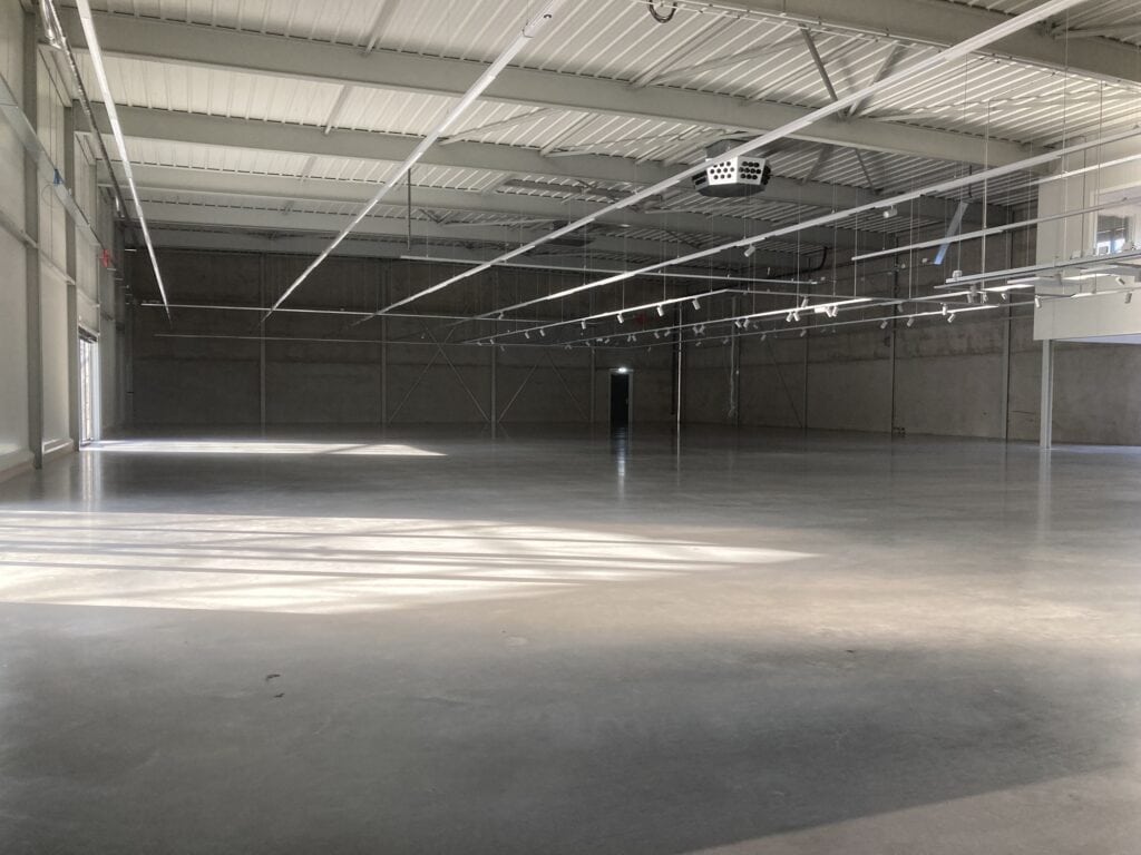 Grote lege industriële hal met hoge plafonds en veel lichtinval.