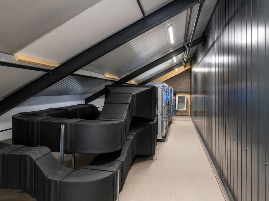Zolderruimte met isolatie, ventilatie en zwarte wandbekleding.