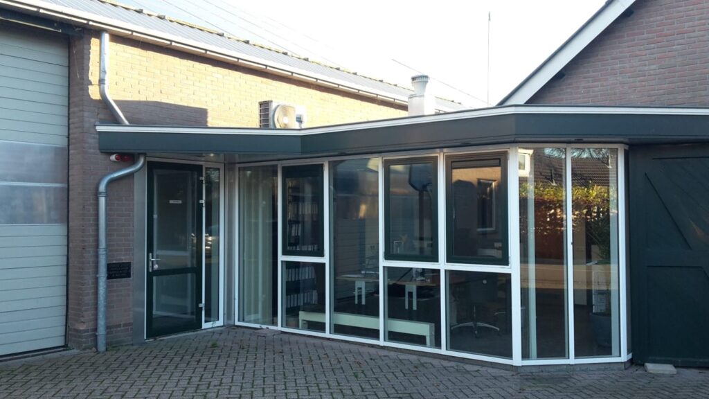 Moderne serre uitbreiding door JCVANKESSEL Bouw met grote ramen en glazen deuren.