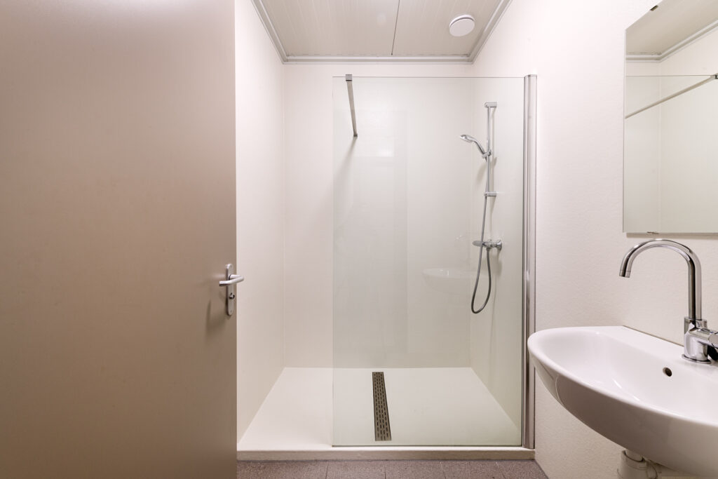Strakke inloopdouche met glazen wand en moderne afwerking.