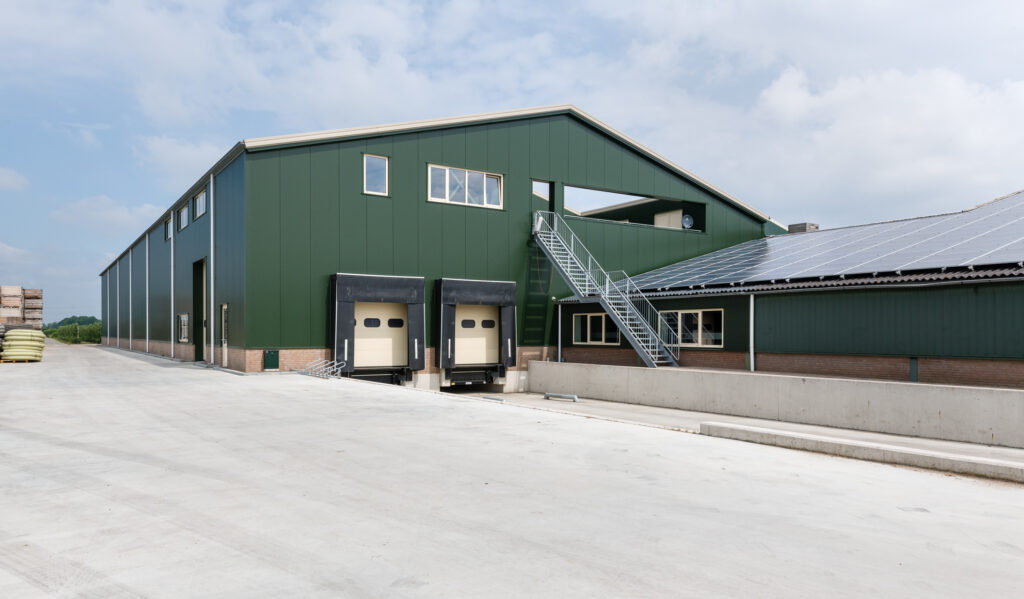 Groene industriële loods met laadperrons en externe trap.