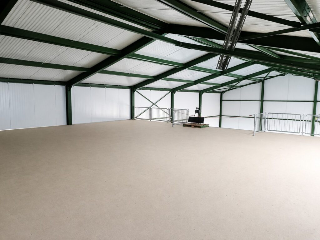 Ruime industriële hal met metalen structuur en betonnen vloer.