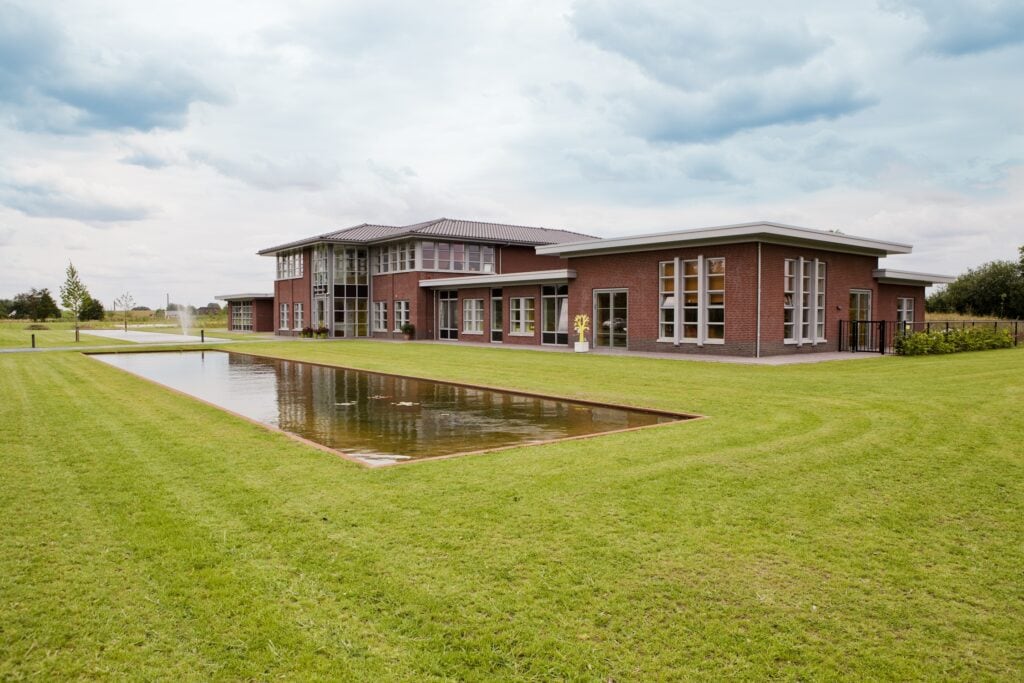 Modern bouwproject met waterpartij en groene omgeving.
