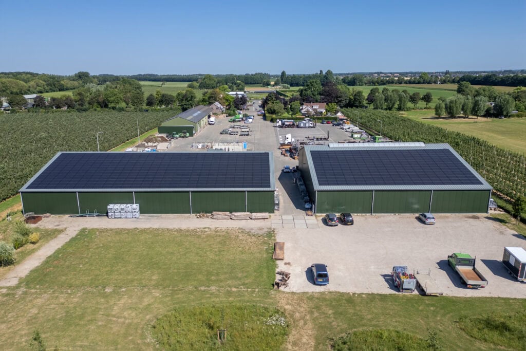 Bedrijfspand met zonnepanelen en opslagruimte in landelijke omgeving.