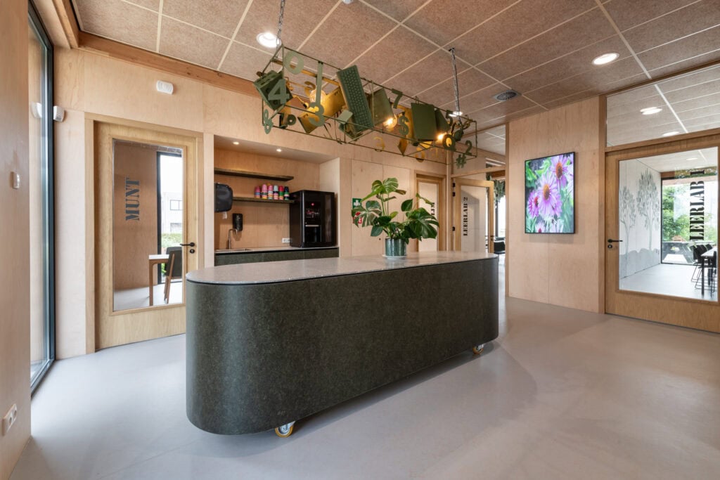 Modern interieur met bar, planten en digitale schermen in Leerlab Rivierenland.