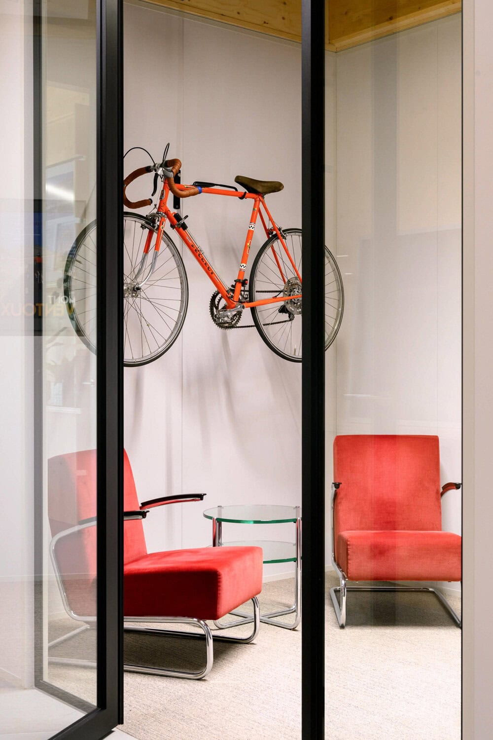 Fiets als decoratie in modern interieur met rode stoelen.