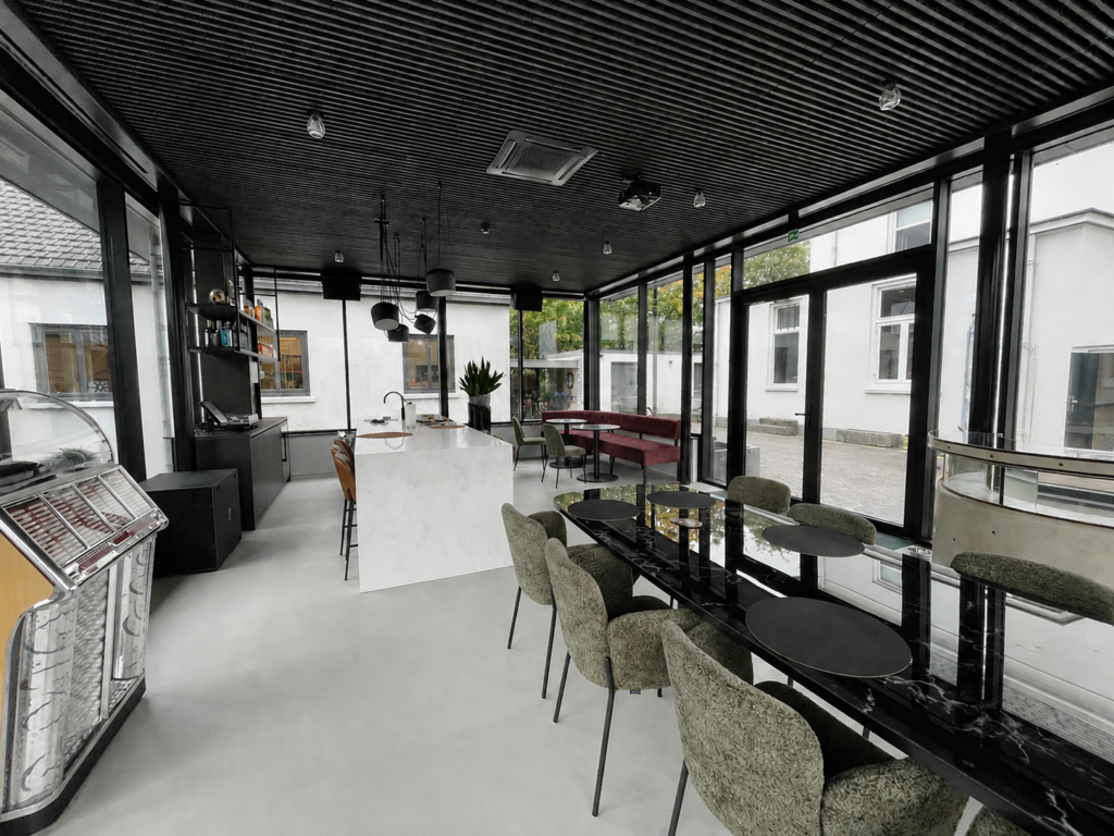 Moderne eetruimte met grote ramen, zwarte plafond en comfortabele stoelen.