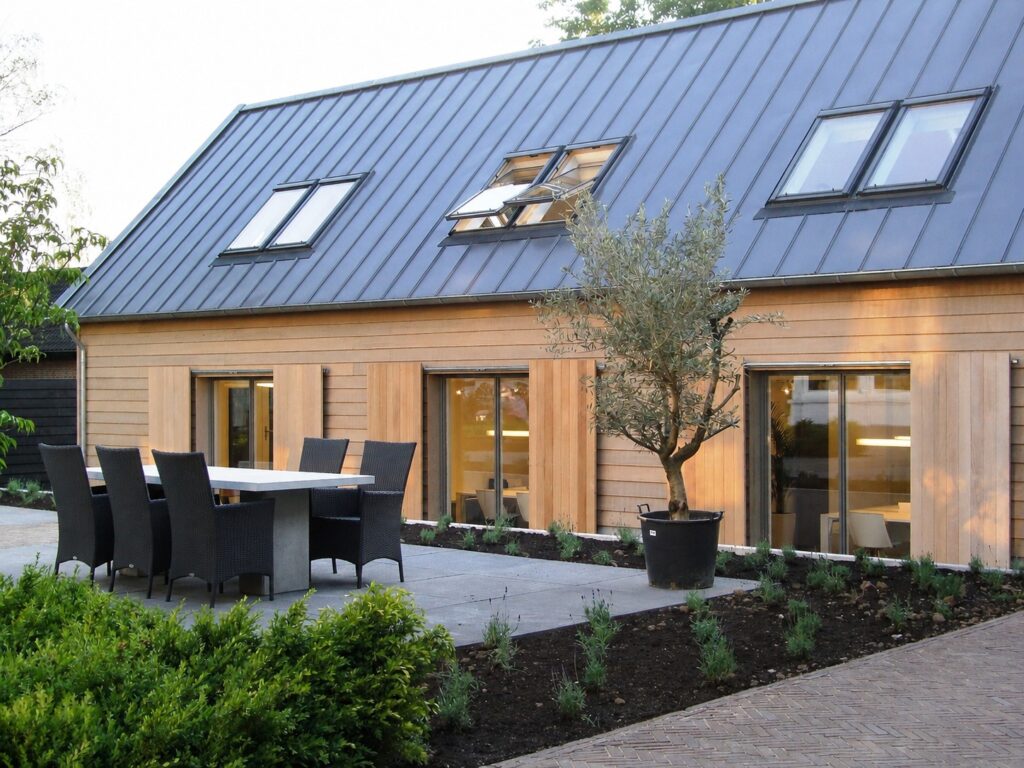 Houten woning met grote ramen en tuinmeubilair in de tuin.