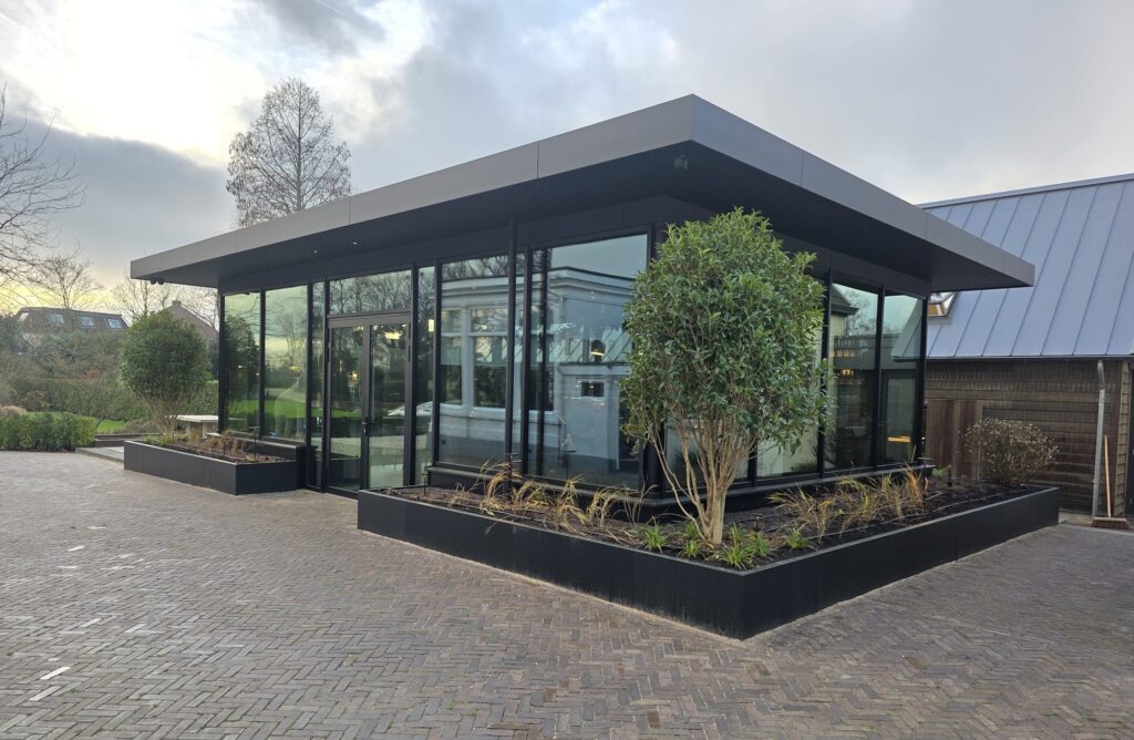 Moderne glazen bouw met strakke lijnen en groene planten.