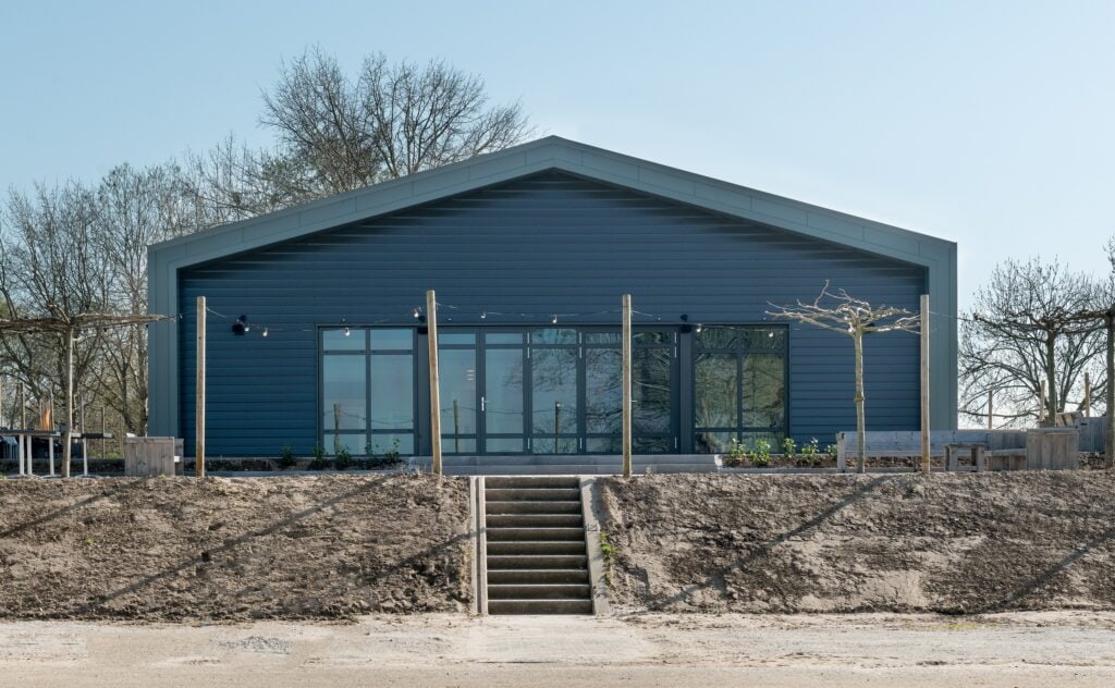 Moderne blauwe bouwconstructie met grote glazen deuren en omheining.