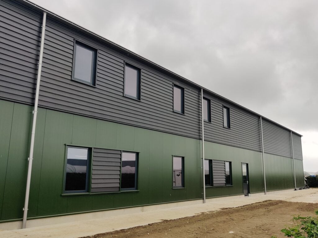 Nieuw bedrijfspand met groene en grijze gevels voor JCVANKESSEL BOUW.