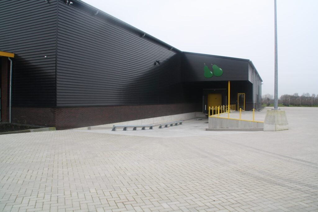 Modern bedrijfsgebouw met zwarte gevel en parkeerplaats.