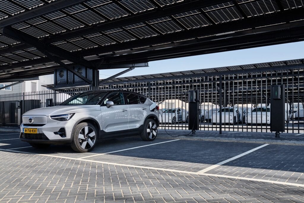 Elektrische auto bij laadstation onder zonnepanelen.