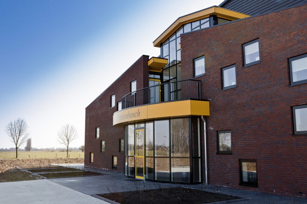 Moderne woning met rode bakstenen en grote ramen door JCVANKESSEL BOUW.