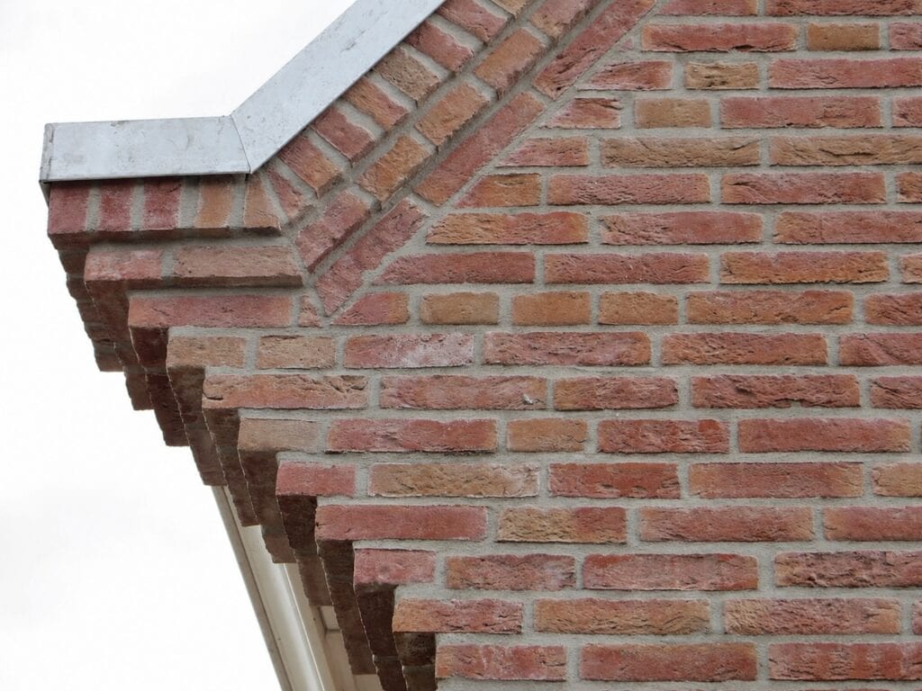 Close-up van een bakstenen gevel met sierlijke metselwerkdetails.