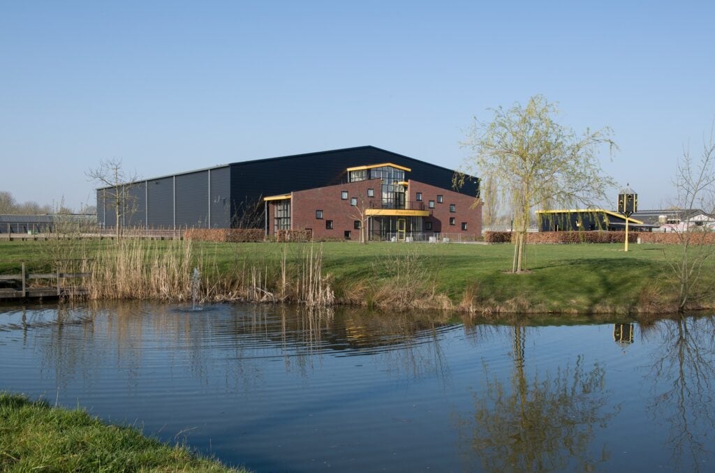 Modern industrieel gebouw aan water met groene omgeving.