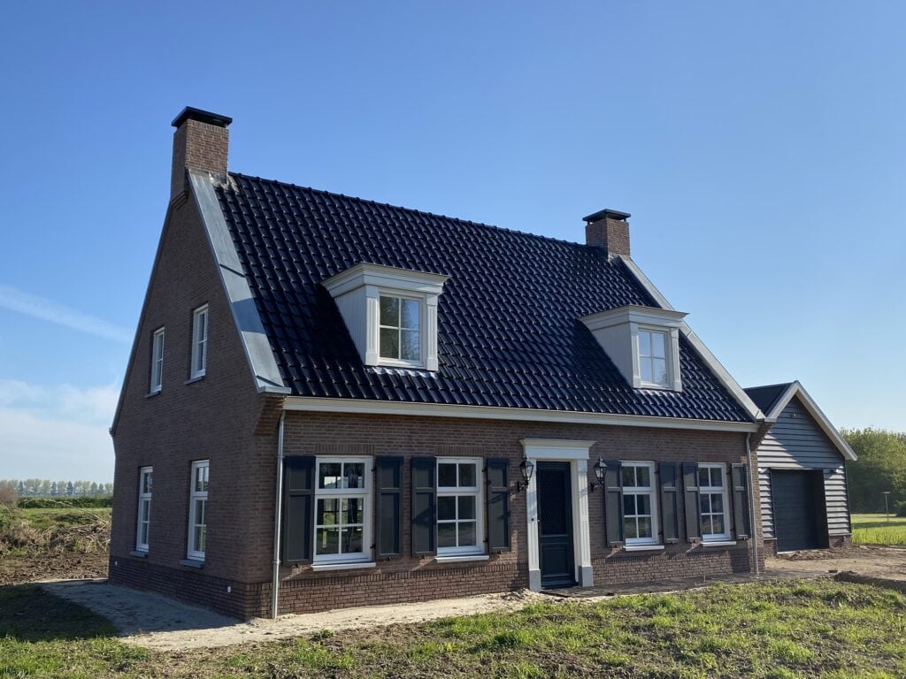 Traditionele notariswoning met bijgebouw en tuin, helder blauwe lucht.
