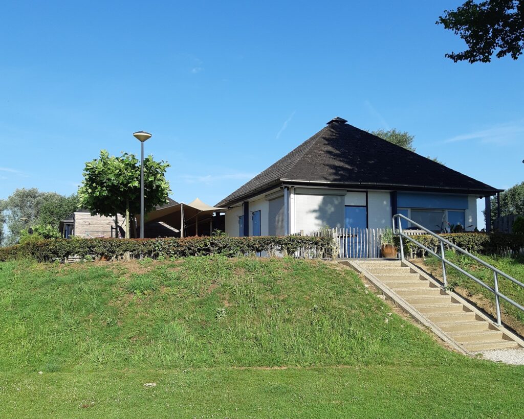 Moderne woning met tuin, terras en trap, onder een heldere blauwe hemel.