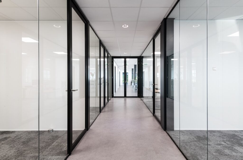 Kantoor met glazen scheidingswanden en moderne inrichting.