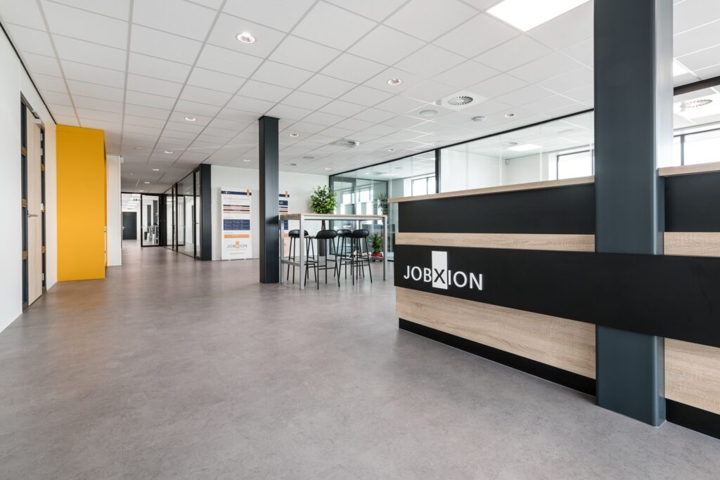 Modern kantoorruimte van JCVANKESSEL BOUW met ontvangstbalie en zitgedeelte.