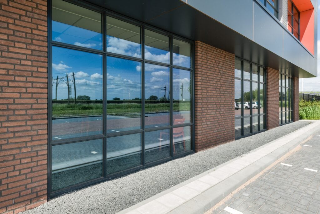 Moderne bedrijfspand met grote glazen ramen en brick gevel.
