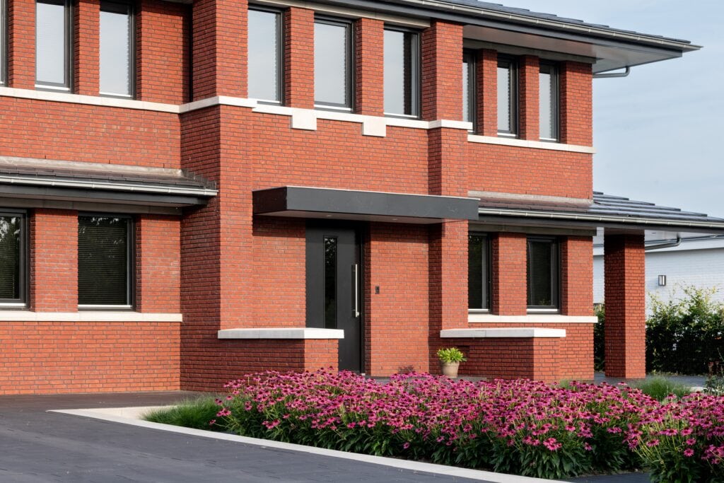 Nieuwbouw woning in Noordijk met rode bakstenen en grote ramen.