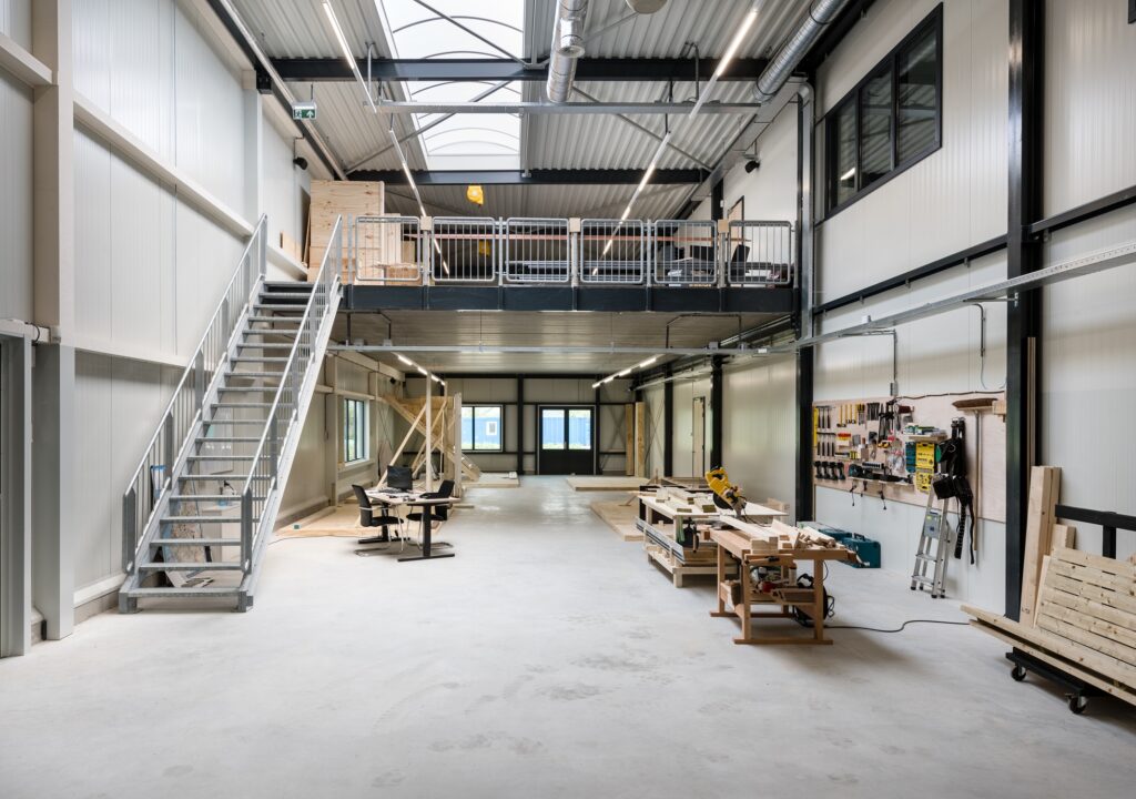 Moderne industriële werkruimte met mezzanine en werkbanken.