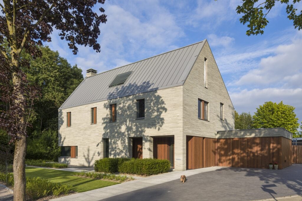 Moderne villa met strakke lijnen en grote ramen in een groene omgeving.