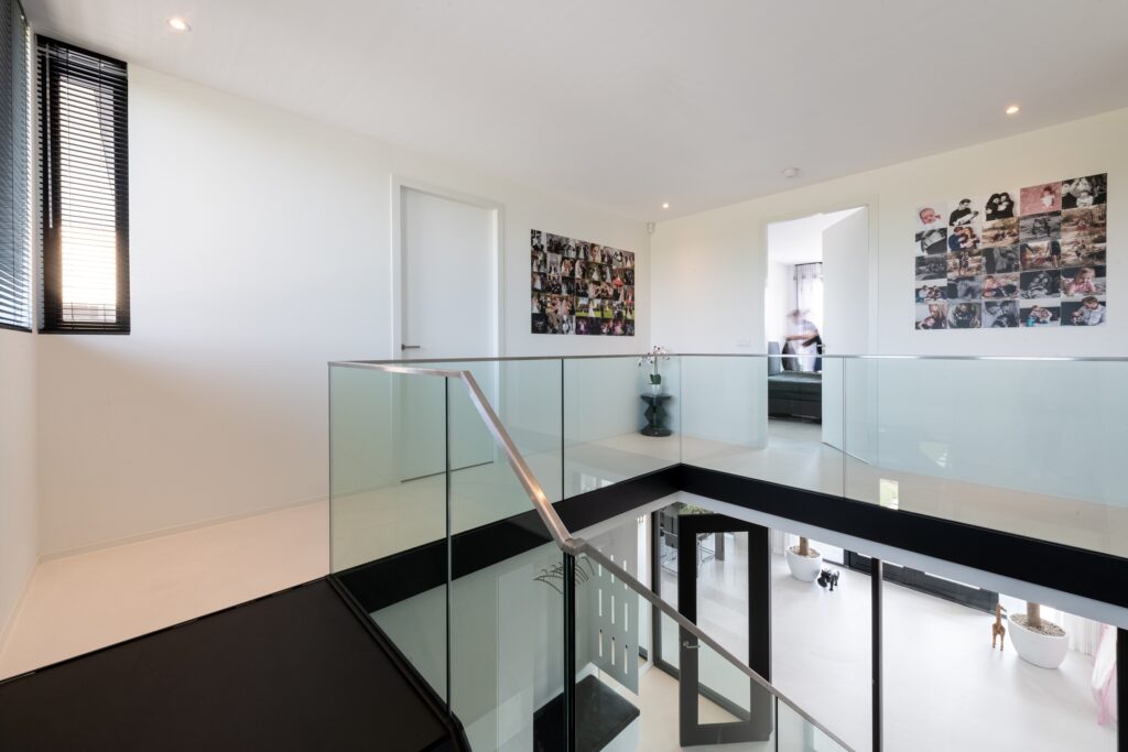 Lichte moderne binnenruimte met glazen balustrade en kunstwerken.