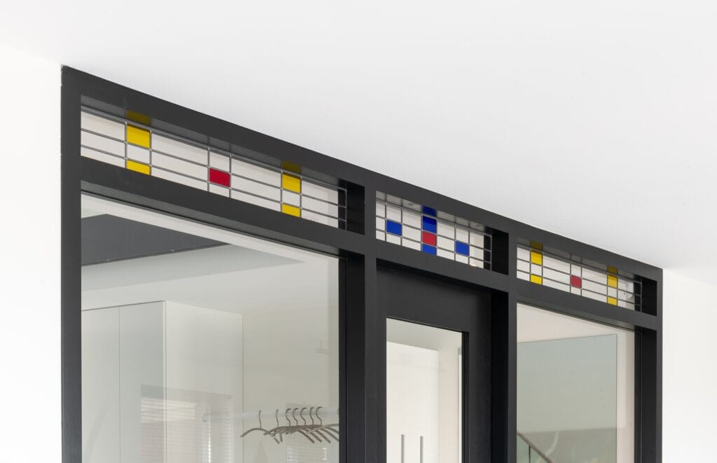 Moderne glasdeur met gekleurde details en zwart frame.
