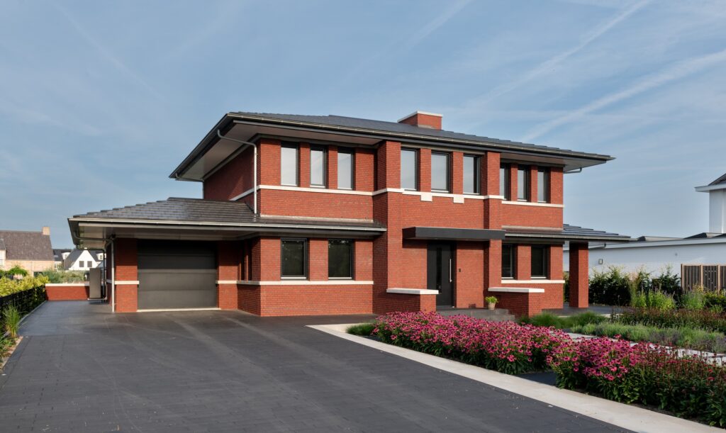 Moderne villa met rode bakstenen gevel en grote ramen.