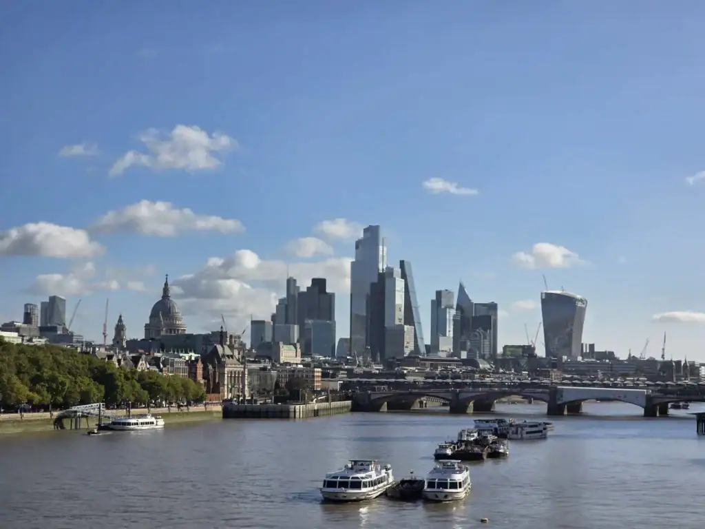 Londen skyline met rivier en boten, helder blauwe lucht.
