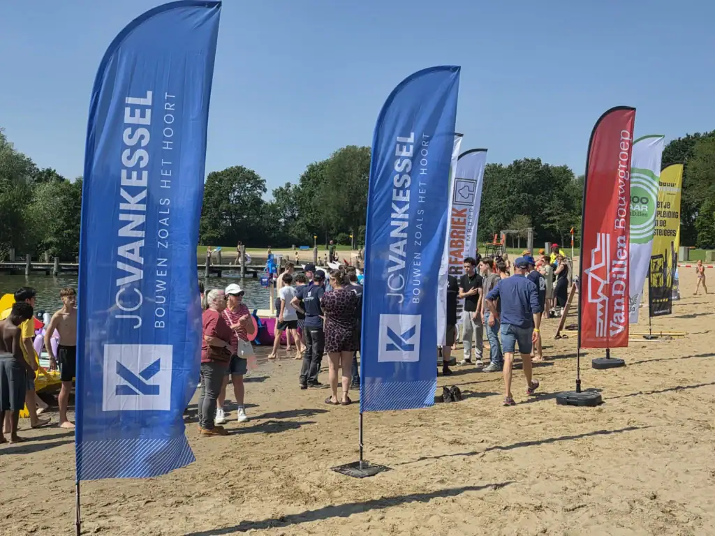 Groep mensen bij bouwpromotie evenement met JCVANKESSEL vlaggen.