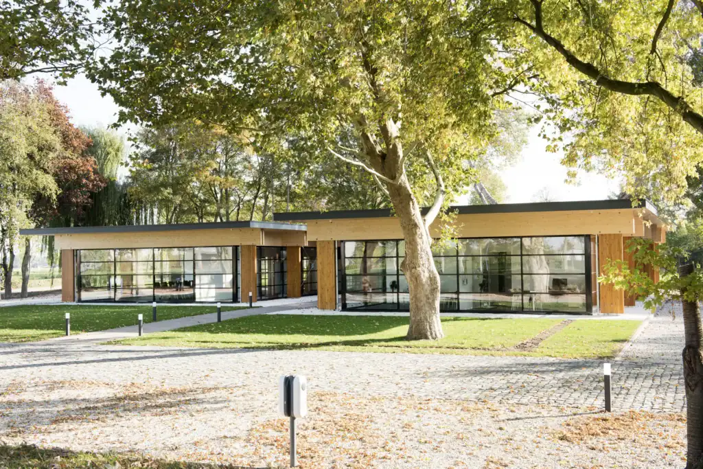 Moderne kantoorruimte met grote ramen en houten details in een groene omgeving.