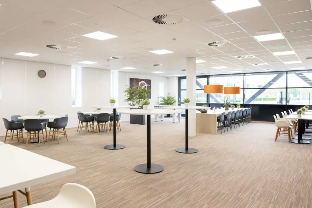 Moderne kantoorruimte met grote ramen, zitplaatsen en planten.