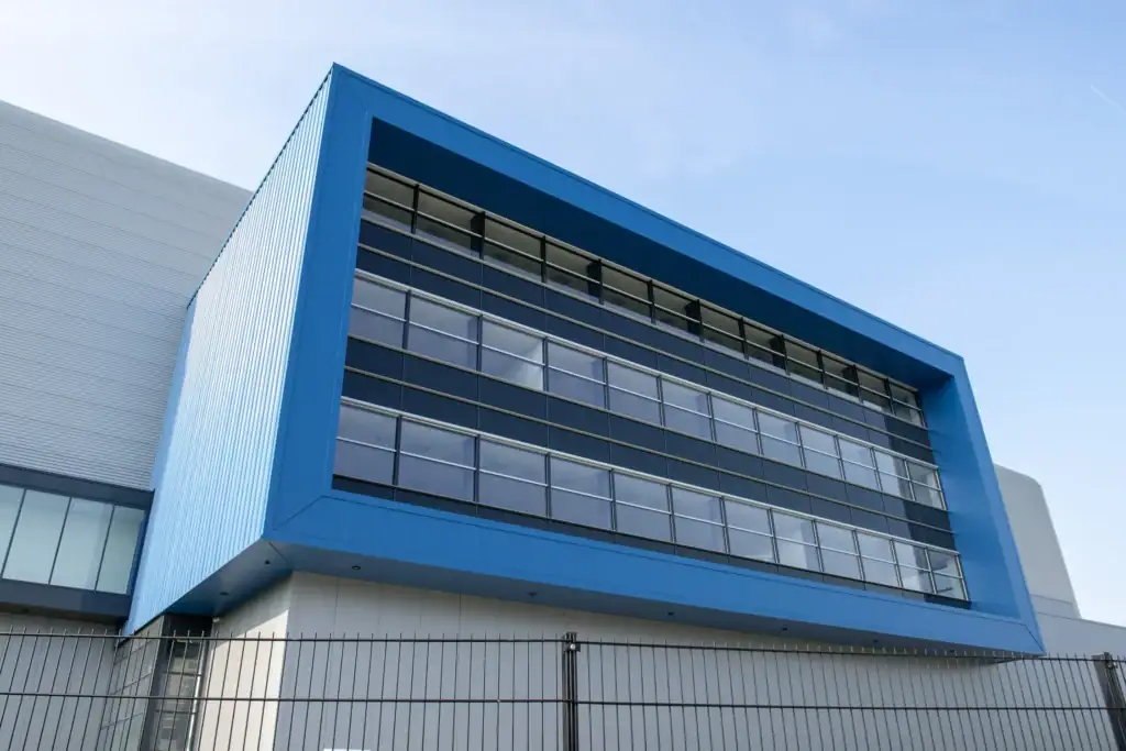 Moderne kantoorgebouw met blauwe gevel en grote ramen.