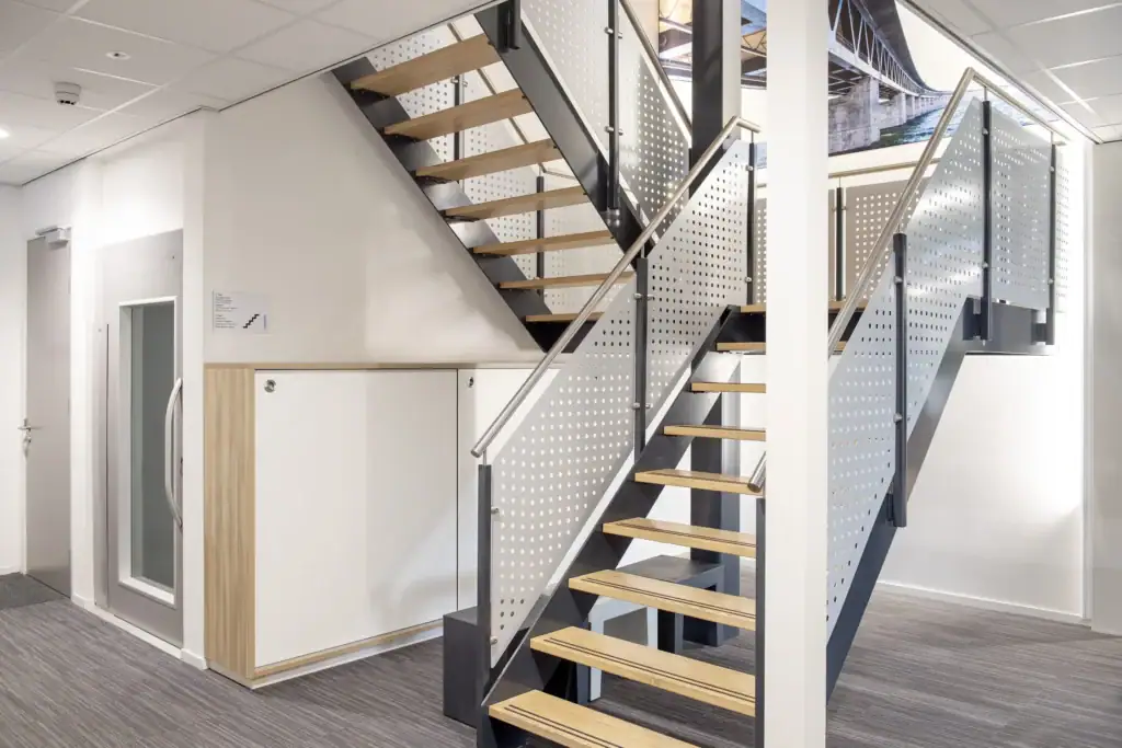 Moderne trap met houten treden en metalen leuning in kantooromgeving.